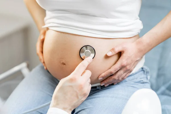 Médico ouvindo uma barriga de mulheres grávidas — Fotografia de Stock