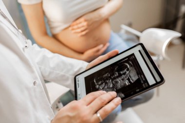 Muayene sırasında doğmamış çocuğun ultrason taraması yapan bir doktor.