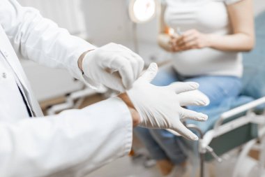 Doktor ameliyattan önce tıbbi eldiven giyiyor.