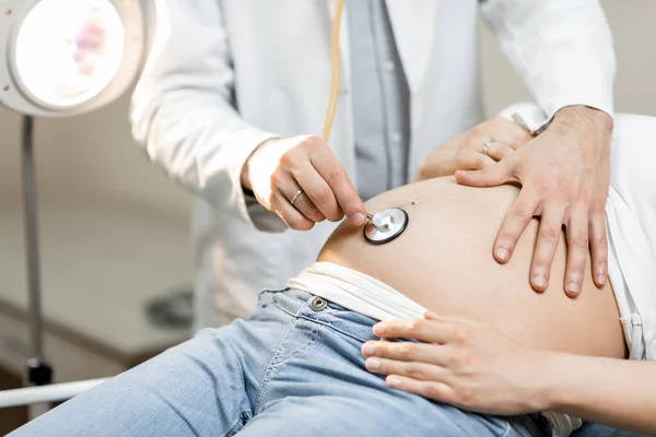 Doctor listening to a pregnant womans belly — Stock Photo, Image