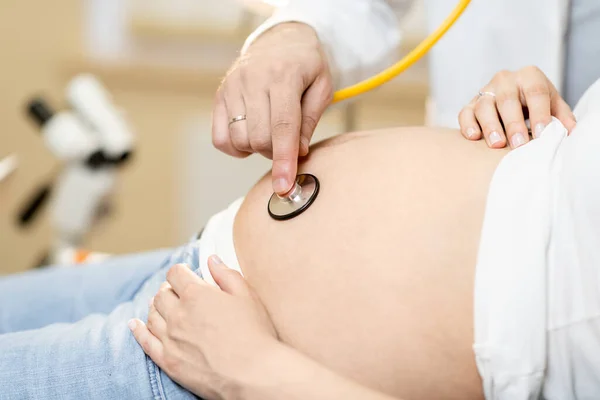 Doctor listening to a pregnant womans belly — Stock Photo, Image