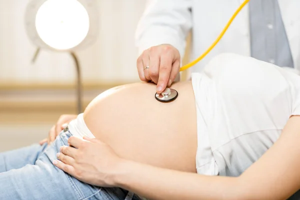 Médico ouvindo uma barriga de mulheres grávidas — Fotografia de Stock
