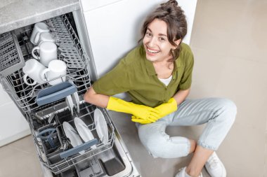Ev hanımı bulaşık makinesinin yanında.