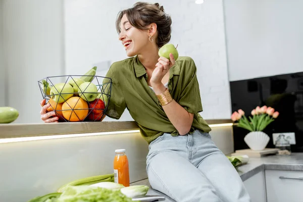 Retrato de uma jovem mulher com comida saudável na cozinha — Fotografia de Stock