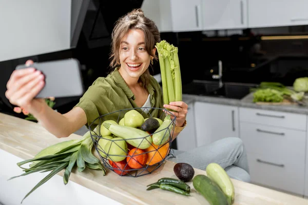 Mulher com comida saudável e telefone na cozinha em casa — Fotografia de Stock