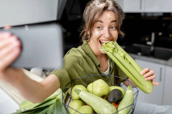 Mulher com comida saudável e telefone na cozinha em casa — Fotografia de Stock