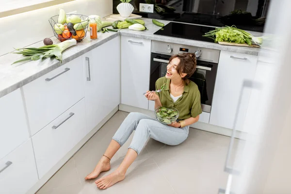 Mulher comendo salada saudável na cozinha em casa — Fotografia de Stock