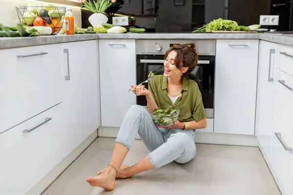 Mujer comiendo ensalada saludable en la cocina en casa — Foto de Stock