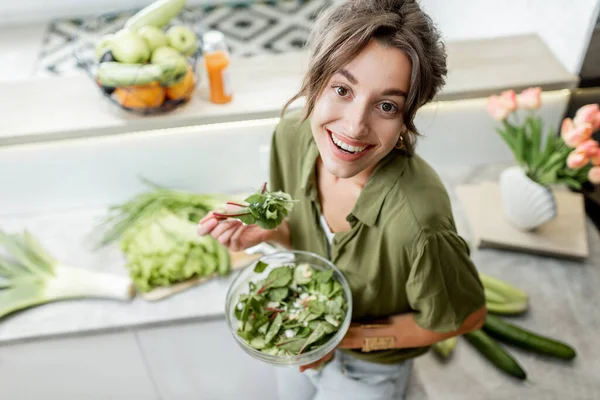 Mujer comiendo ensalada en la cocina en casa — Foto de Stock