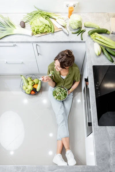 Mulher comendo salada saudável na cozinha em casa — Fotografia de Stock