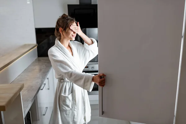 Vrouw kijkt 's nachts in de koelkast op de keuken — Stockfoto