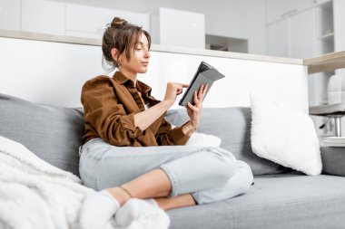 Evdeki kanepede tabletli bir kadın.