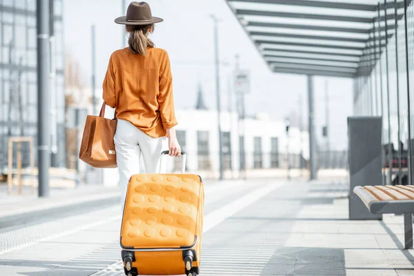 Νεαρή γυναίκα ταξιδιώτισσα με μια βαλίτσα στη στάση μεταφοράς — Φωτογραφία Αρχείου
