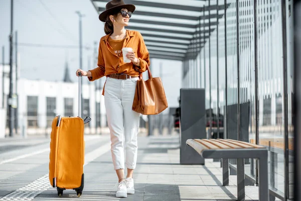 Giovane viaggiatrice con un bagaglio alla fermata del trasporto — Foto Stock