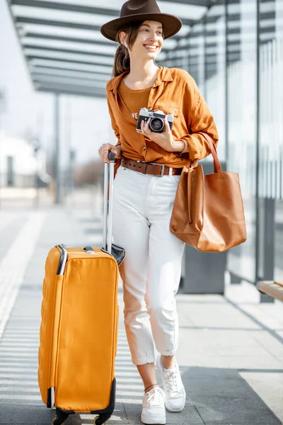 Giovane viaggiatrice con un bagaglio alla fermata del trasporto — Foto Stock