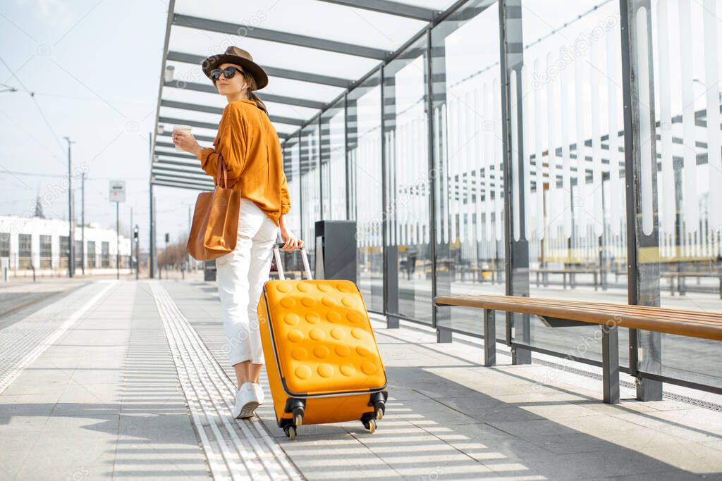 Young female traveler with a luggage at the transport stop