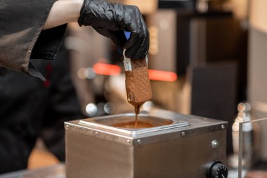 Şef dondurmayı erimiş çikolataya daldırıyor.