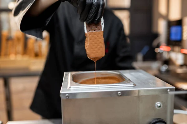 Chef plonge la crème glacée dans le chocolat chaud fondu — Photo