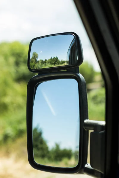 Kamyon kontrol paneli ile sürücünün direksiyon simidi ve yan dikiz aynası gece gökyüzü günbatımı ile karşı taraftan