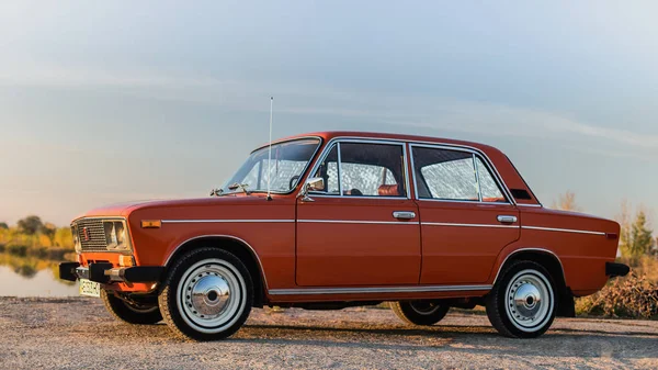 PERESHCHEPINO, UKRAINE - OCTOBER 12, 2014: Zhiguli VAZ 2106 original orange, released in the USSR in 70's. Car parked on the side of the road in the middle of sunny day without cars nearby