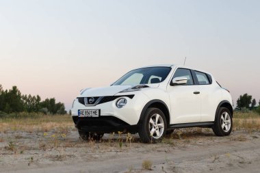 Novoselivka, Dnipropetrovsk bölgesi, Ukrayna - Temmuz 02, 2020: Nissan Juke 2019 Alacakaranlıktaki kırsal yol yakınlarındaki beyaz renk