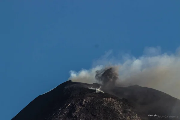 Etna volcano erupting from main crater with smoke and ash -and clear blue sky in background