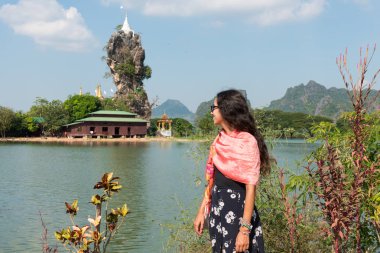 Hpa-An, Myanmar - 19 Kasım 2018: Hpa An, Myanmar'da uçurumun üzerine inşa edilen Kyaut Ka Latt Pagoda'ya bakan genç kadının yatay resmi