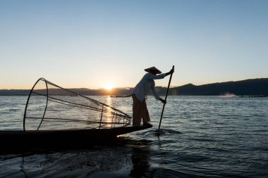 Inle Lake, Myanmar - 30 Kasım 2018: Myanmar'ın Inle Gölü'nde gün batımını zıt kürekli ve geleneksel net siluetli birmanyabalıkçılarının geniş açılı resmi