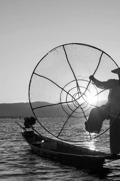 Black and white picture of burmese traditional net silhouette contrasting the sunset at Inle Lake, Myanmar