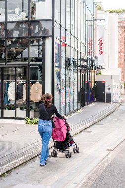 TOKYO, JAPONYA - 27 EKİM, 2024 - Harajuku 'da Cat Street' te bebek arabasıyla gezen bir kadının dikey fotoğrafı.