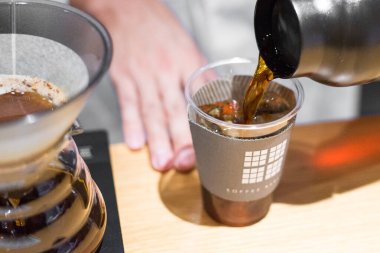 TOKYO, JAPAN- 27 Ekim 2024: Tokyo 'nun merkezindeki ünlü Mameya kahve dükkanında plastik bir fincanda filtrelenmiş kahvenin yatay resmi