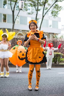 TOKYO, JAPONYA - 27 EKİM, 2024 - Tokyo 'da Omotesando Cadılar Bayramı' nda balkabağı giymiş Japon bir kadının dikey fotoğrafı.