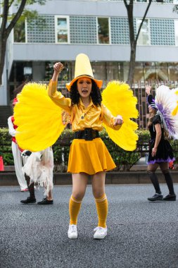 TOKYO, JAPONYA - 27 Ekim 2024 Tokyo 'da Harajuku Mahallesi' nde her yıl düzenlenen bir etkinlik olan Omotesando Cadılar Bayramı 'nda Japon bir kadının dans ettiği, sarı kostümlü bir cadı resmi.