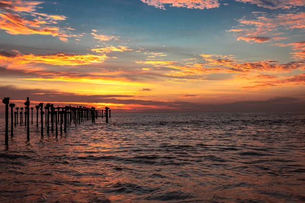 Nube naranja en el horizonte del mar con los principales postes de hierro — Foto de Stock