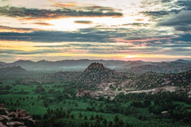 Matanga Hill hampi karnataka Hindistan 'da sabah düz açıyla çekilen dramatik gökyüzü ile dağ gündoğumu alevleri. Buradan manzara sakin ve nefes kesici..