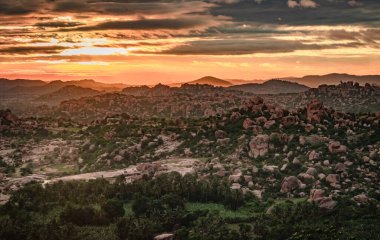 Matanga Hill hampi karnataka Hindistan 'da sabah düz açıyla çekilen dramatik gökyüzü ile dağ gündoğumu alevleri. Buradan manzara sakin ve nefes kesici..