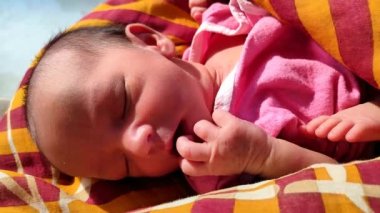 Güneşli bir günde uyurken yeni doğmuş şirin bebek yüz ifadesi bir bebeğin doğal masumiyetini gösteriyor.