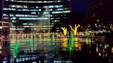Su çeşmesi şehir meydanında gece renkli ışıklar gösteriyor.