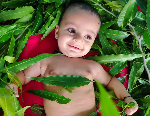 幼い子供が葉で遊んでかわいい顔の表情を見せて — ストック写真