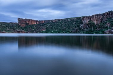 Dağın arka planında el değmemiş göl ve alacakaranlık görüntüsüne uzun süre maruz kalan gökyüzü Agastya Tirtha 'nın Badami Karnataka Hindistan kıyılarındaki Bhutanatha Tapınağı' nın güzelliğini gösteriyor..