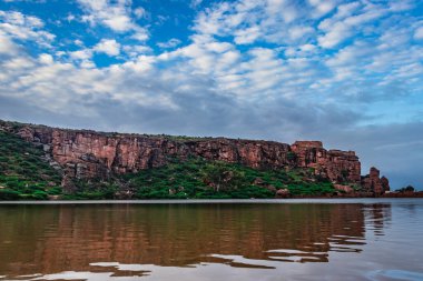 Dağ zeminine ve parlak gökyüzüne sahip saf göl, Badami Karnataka Hindistan 'ında Agastya Tirtha kıyılarındaki Bhutanatha Tapınağı' nın güzelliğini gösteriyor..