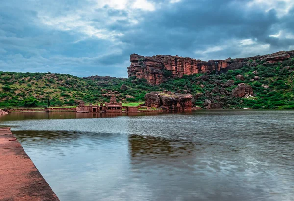 Dağ arkası ve parlak gökyüzü ile el değmemiş gölün şafak vakti görüntüsü Agastya Tirtha 'nın Badami Karnataka Hindistan kıyılarındaki Bhutanatha Tapınağı' nın güzelliğini gösteriyor..
