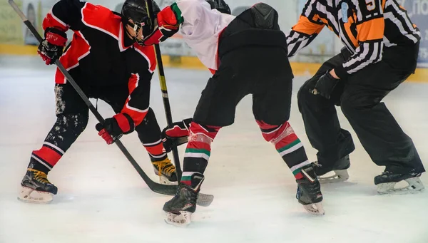 hockey players are preparing to throw the puck on the ice