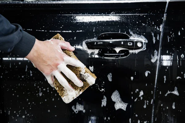 Puerta del coche con espuma y una mano con una esponja de espuma — Foto de Stock