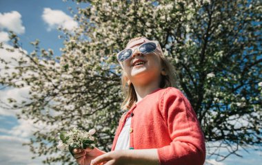 Güneş gözlüklü neşeli kız gökyüzüne bakıyor