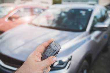 Uzaktan kumandalı bir el ve arka planda sığ bir alan derinliğinde bir araba.