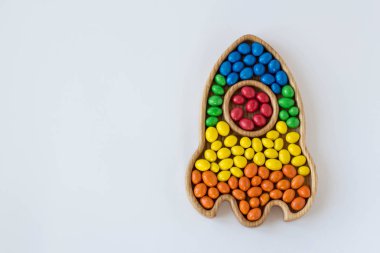 beyaz bir arka plan üzerinde bir roket şeklinde kırmızı, sarı, yeşil, mavi, turuncu farklı renklerde şeker dragees. konsept bayrak gökkuşağı lgbtq topluluğunun gökkuşağı bayrağının renkleri gurur