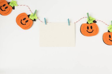 Yaratıcı Cadılar Bayramı kompozisyon düz üst görünüm tatil kutlama turuncu kabaklar, beyaz kağıt arka plan kopya alanı üzerinde ip üzerinde metin için yer ile beyaz kart yatıyordu