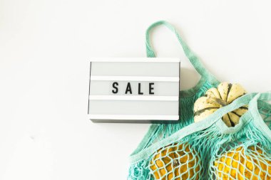 Sonbahar düz beyaz arka plan üzerinde mavi örgü alışveriş çantası beyaz, turuncu kabaklar ile kompozisyon yatıyordu. Yaratıcı sonbahar, şükran, sonbahar, sıfır atık tarzında cadılar bayramı kavramı