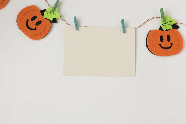 Creative Halloween dag komposition Flat Lay topp Visa semester firande orange pumpor, vitt kort med plats för text på repet på vitt papper bakgrund kopiera utrymme — Stockfoto